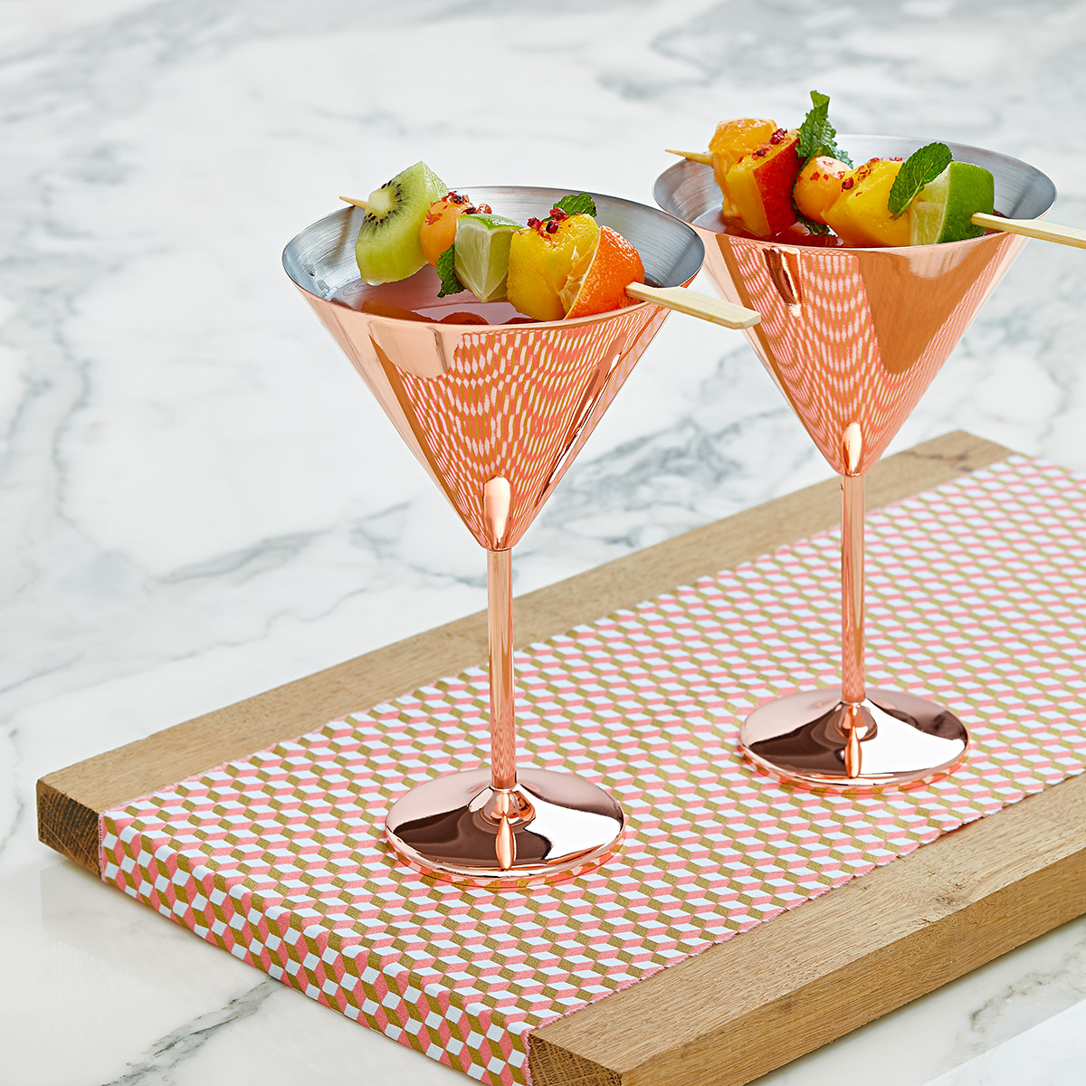 Coupe à cocktail cuivrée, jus  d'agrumes et brochettes de fruits