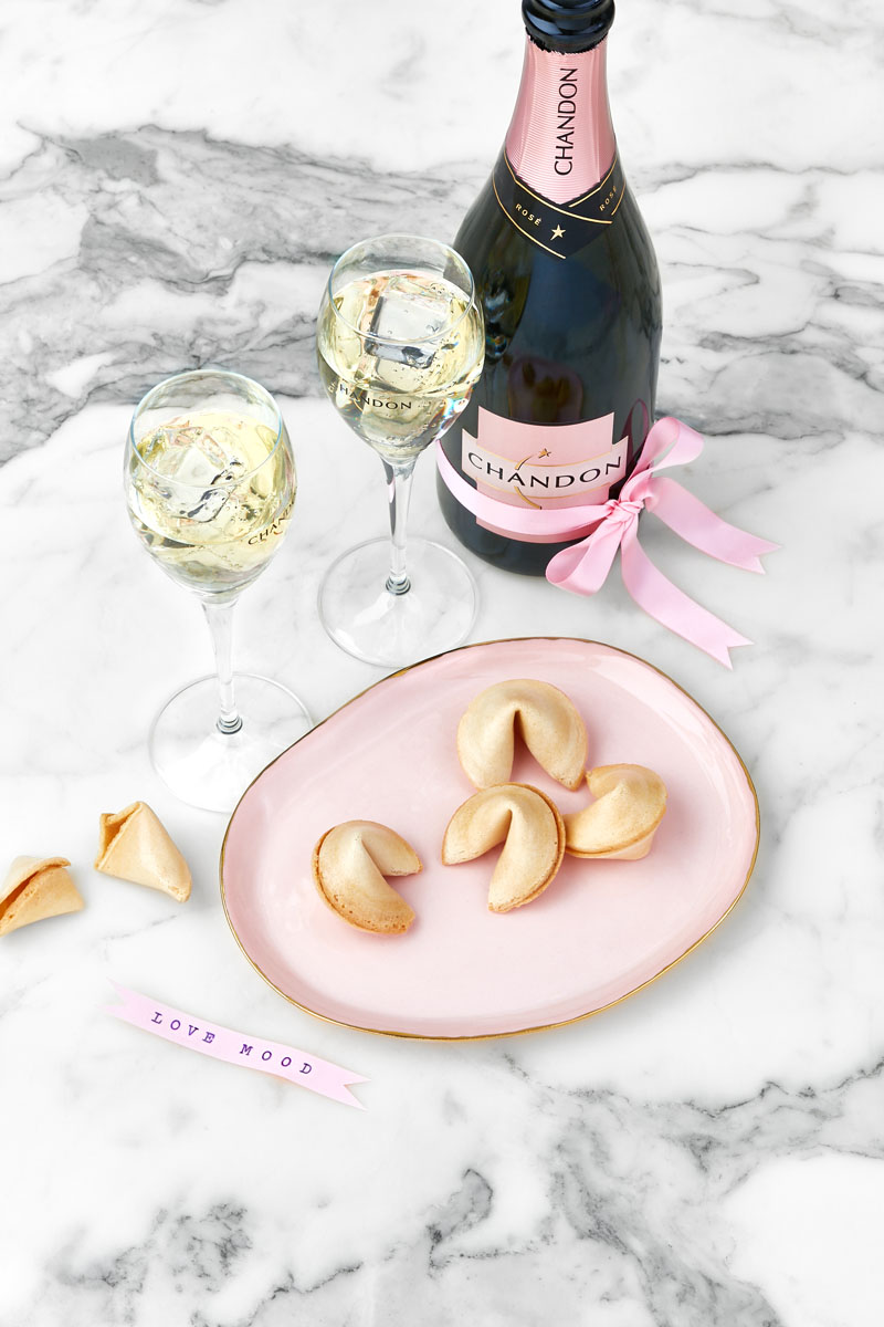 Pétillant rosé et fortune cookies dans un plat rose sur un fond marbre