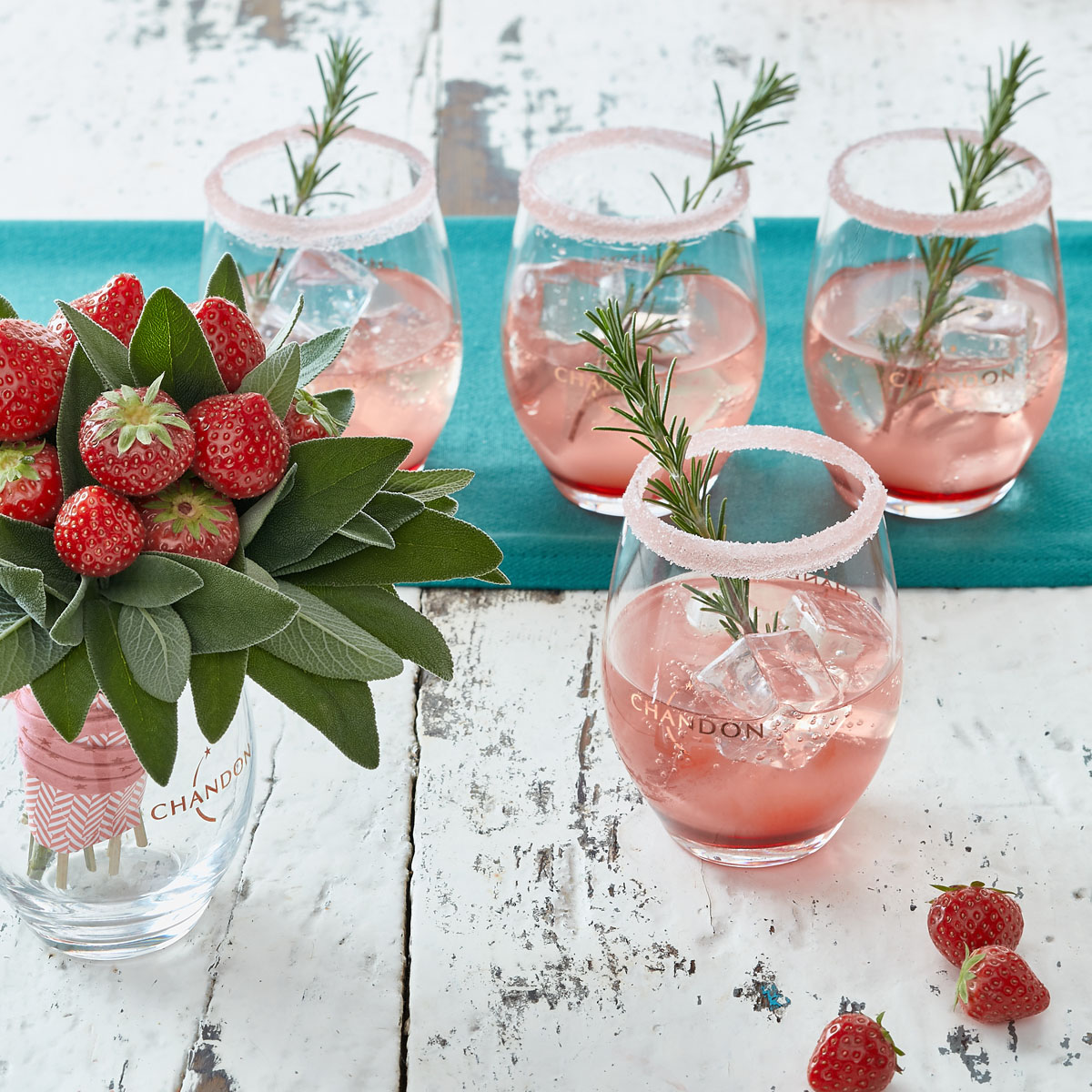 Quatre verres de cocktails pétillant aux fraises et à la sauge avec un bouquet de fraises