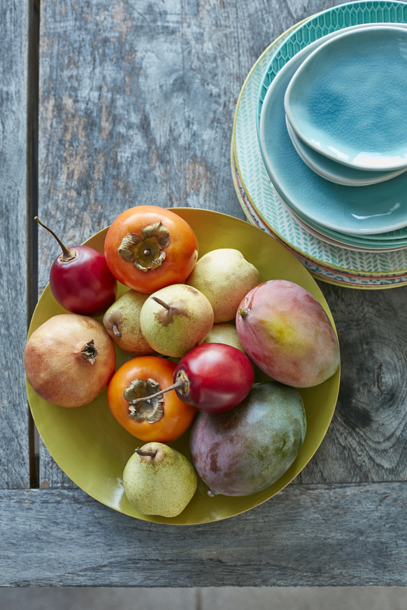 Pile d'assiettes turquoises et coupe de fruits exotiques