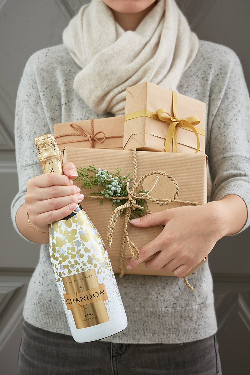 Jeune fille tenant des cadeaux et une bouteille de pétillant